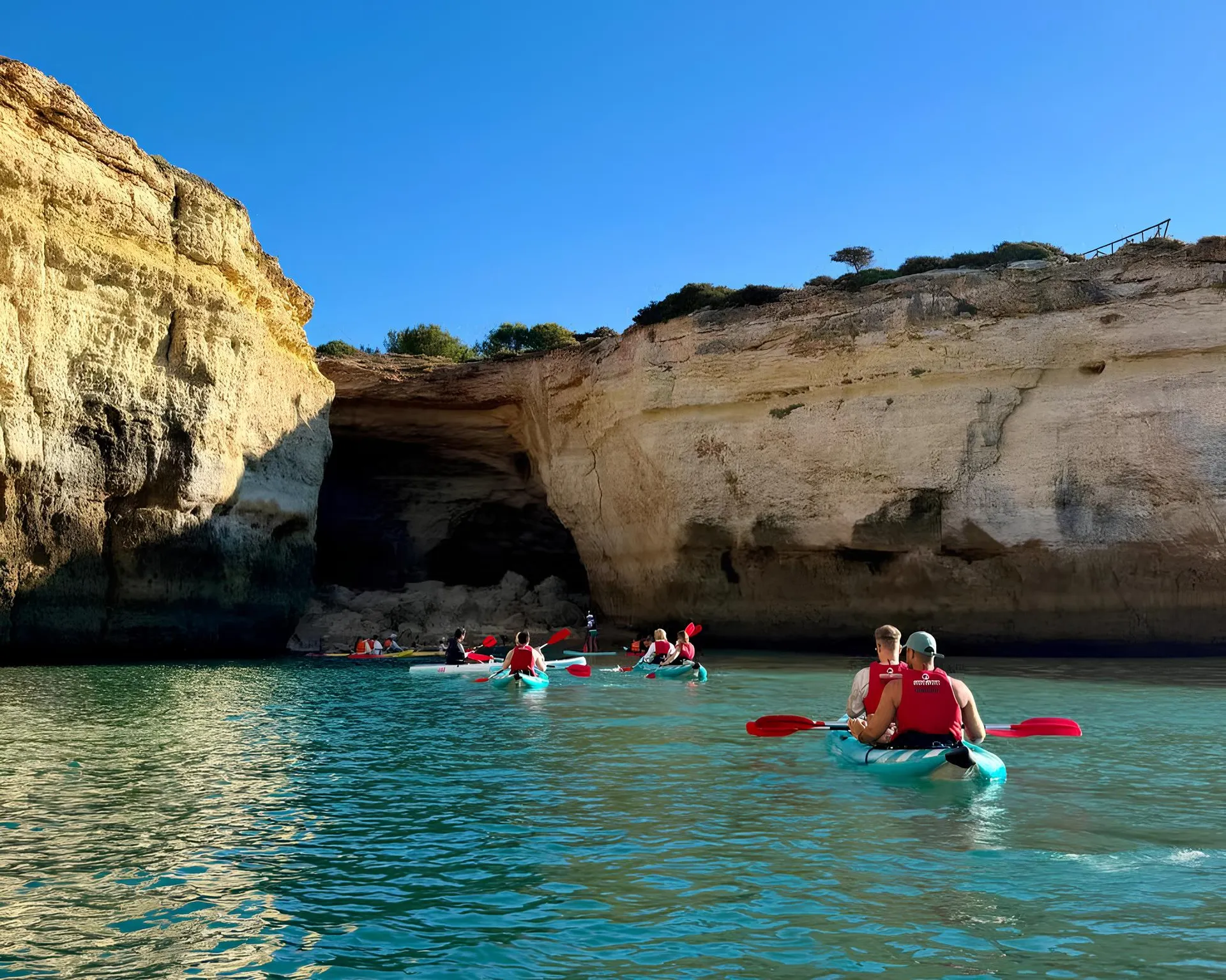 Kayak tour approaching a sea cave entrance along the Algarve coast